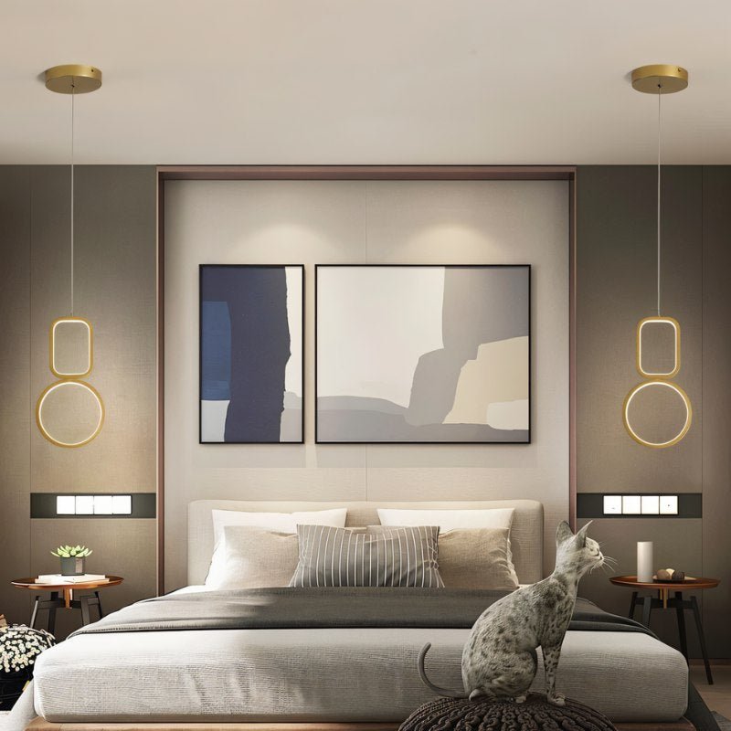 "Pair of geometric pendant lights with metal frames and acrylic diffusers, flanking a bed with a cat sitting in the foreground."