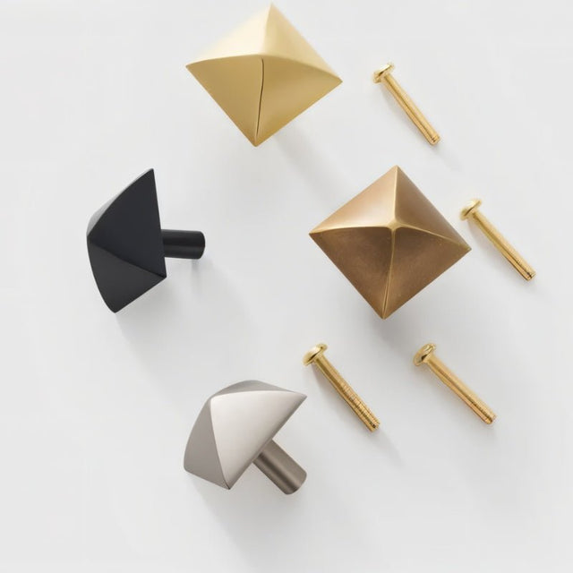 "Assortment of pyramid-shaped brass knobs with screws on a white background."