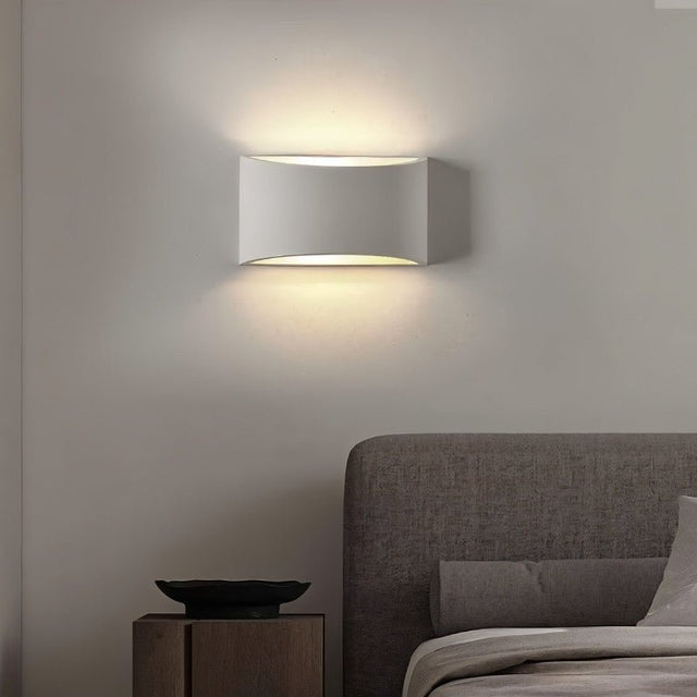 "Modern curved rectangular gypsum wall lamp casting soft light upward and downward in a contemporary bedroom."