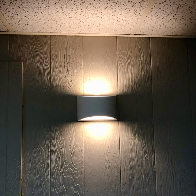 "Modern curved rectangular gypsum wall lamp casting soft light upward and downward on a textured wall."