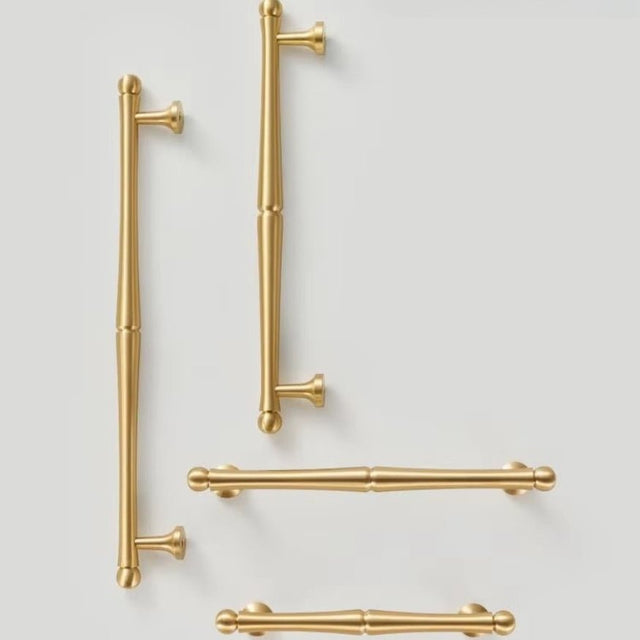 "A collection of brass pull bar handles in various sizes on a light background."