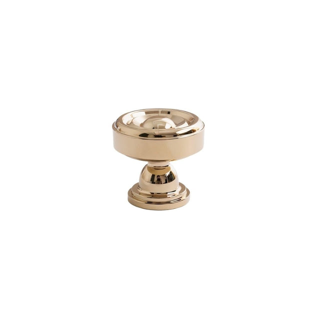 "Brass cabinet knob with a tapered spindle design and intricate finials isolated on a white background."