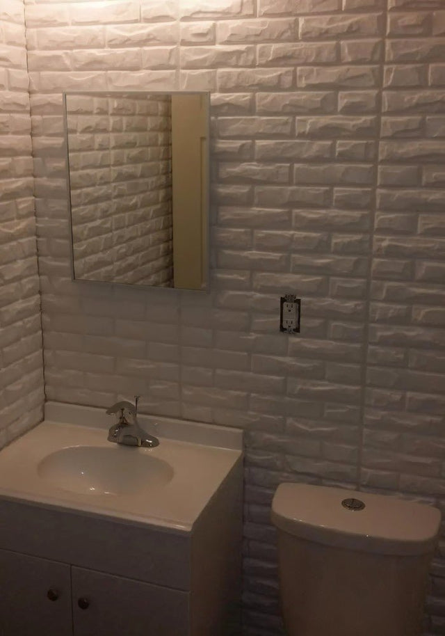 Libtu Wall Panel installed in a bathroom setting, showcasing its white 3D brick texture for modern PVC wall decor.