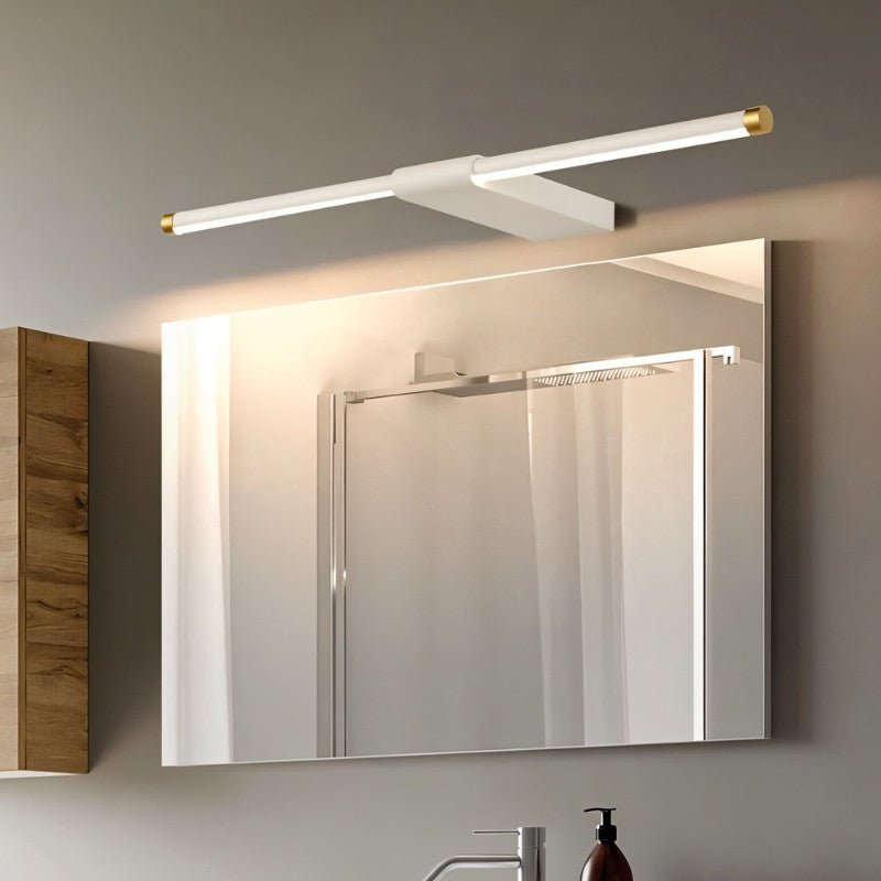 "Modern white Lisorva wall lamp, crafted from metal and PC with brass accents, providing even illumination above a bathroom vanity mirror."