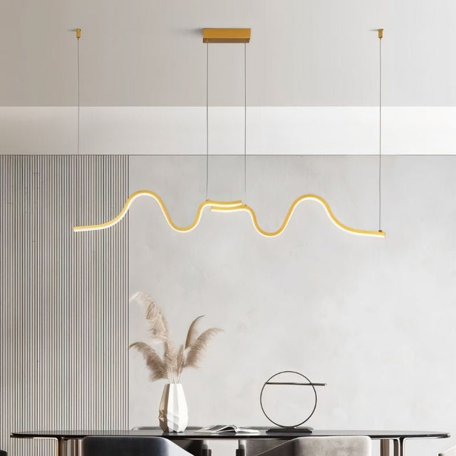 "A gold wave-like pendant light with a sculptural design, suspended above a dining table, providing diffused and elegant illumination."