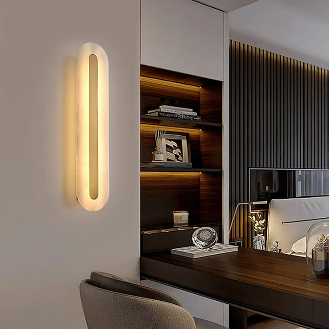 "sleek alabaster and brass wall lamp emitting warm glow in modern interior"