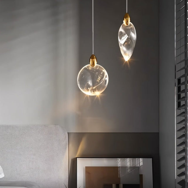 "Two uniquely shaped crystal pendant lights hang in a modern bedroom with a grey accent wall, providing soft, ambient light."