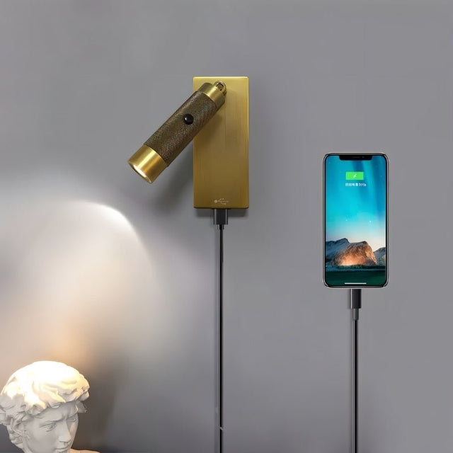 "Wall-mounted bedside reading lamp with adjustable light, polished metal finish, USB connection, and a phone charging via the integrated USB port."