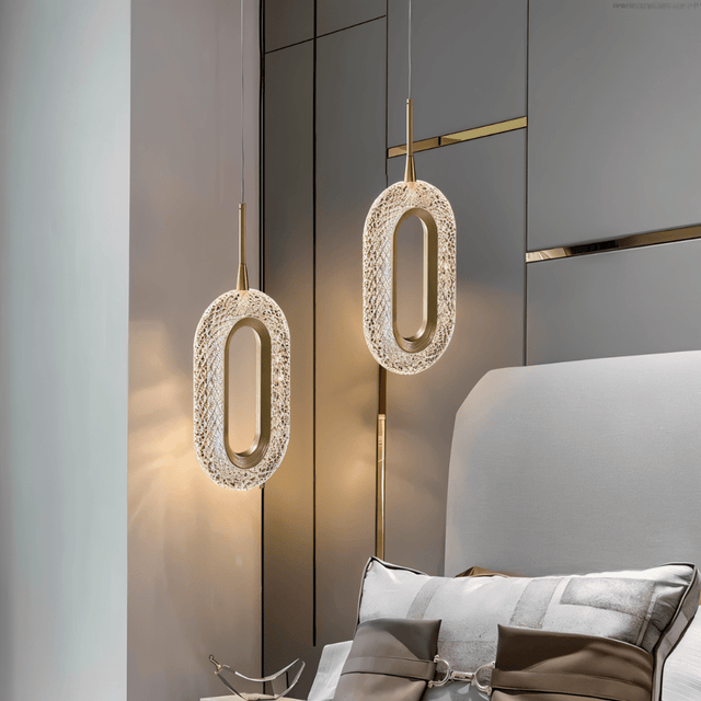 Modern Luxin Pendant Light with sculptural oval design in copper and acrylic, suspended beside a contemporary upholstered bed.