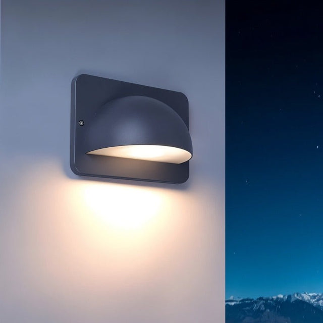 "A modern, dome-shaped outdoor wall lamp casting a soft glow on a wall at night."