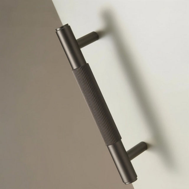 "Modern brass knurled pull handle on a white and gray door or cabinet."