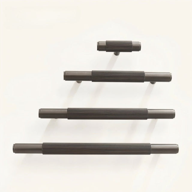 "Modern brass knurled pull handles in various lengths on a white background."