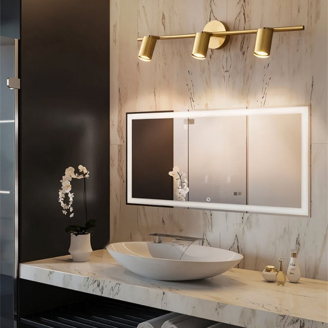 "Modern brass bathroom vanity lighting with three adjustable heads mounted on a circular base above a rectangular mirror."