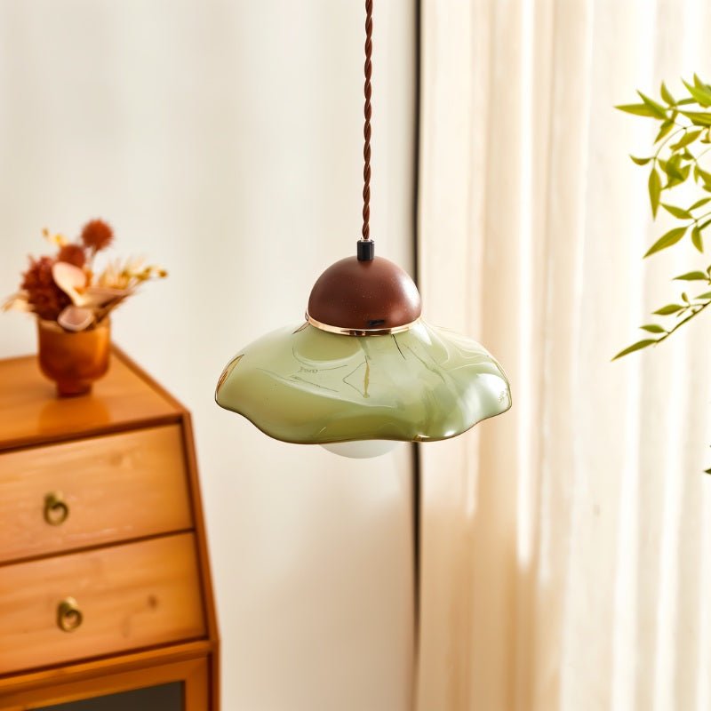 "Handcrafted pendant light with a curved ceramic shade and wooden top in a modern living room, providing warm, ambient lighting."