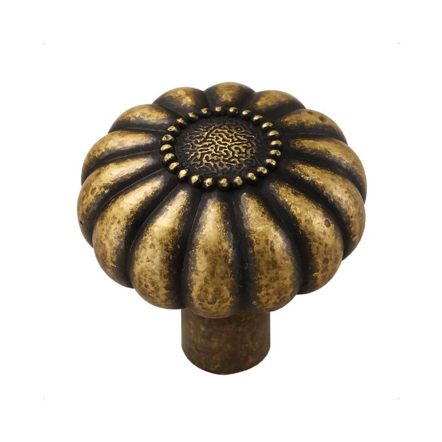 "A vintage brass flower-shaped knob with bold, rounded petals encircling a central medallion, featuring an intricate embossed pattern and a ring of raised dots."