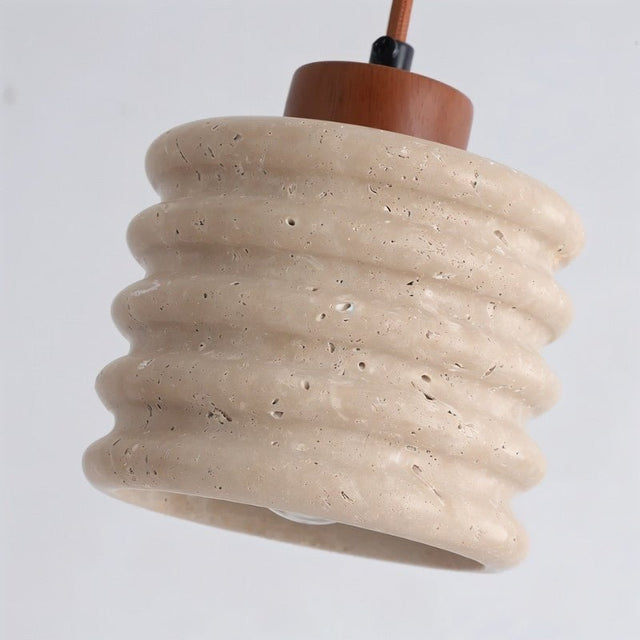 "Close-up of a travertine pendant light with a ribbed design showing texture."