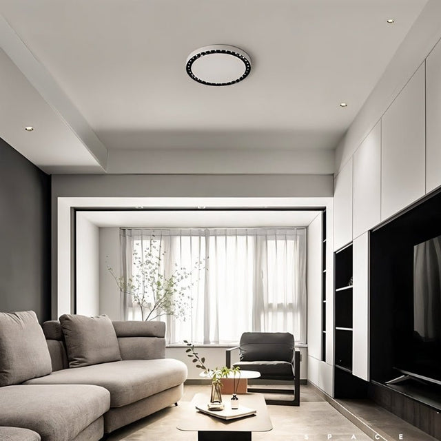 "In this modern living space, the Nival ceiling light's sleek circular design and durable acrylic-aluminum construction provide ambient and accent lighting with its white and dark accents."
