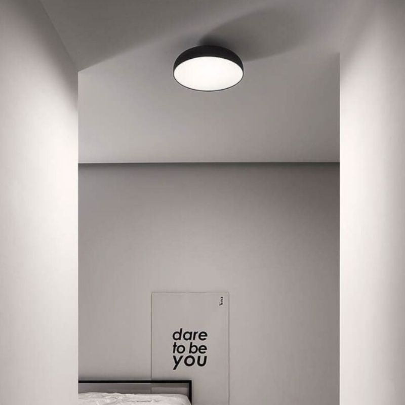 "Minimalist ceiling light fixture in a modern bedroom, featuring a wide, flat design with aluminum and steel construction for optimal light diffusion and a sophisticated, uniform glow."