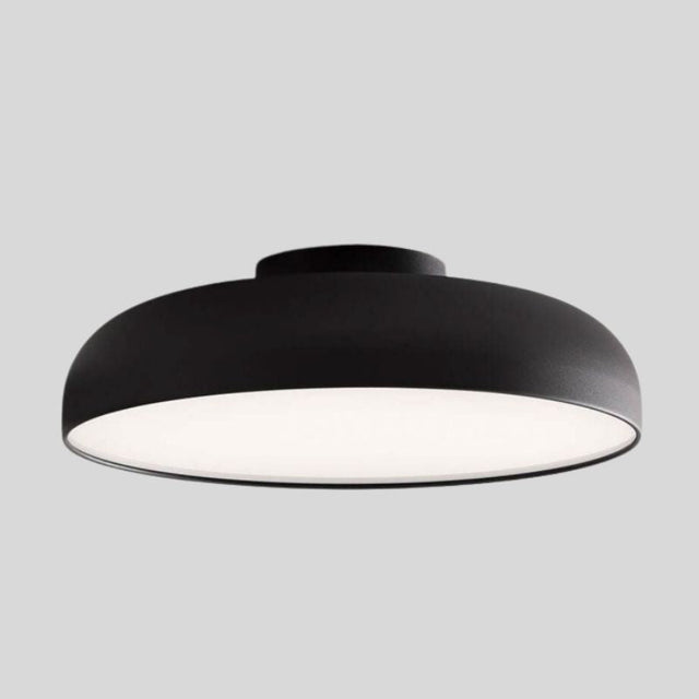 "Close-up view of a sleek Noira ceiling light with a black aluminum and steel finish, featuring a wide, flat design for optimal light diffusion and a minimalist aesthetic."
