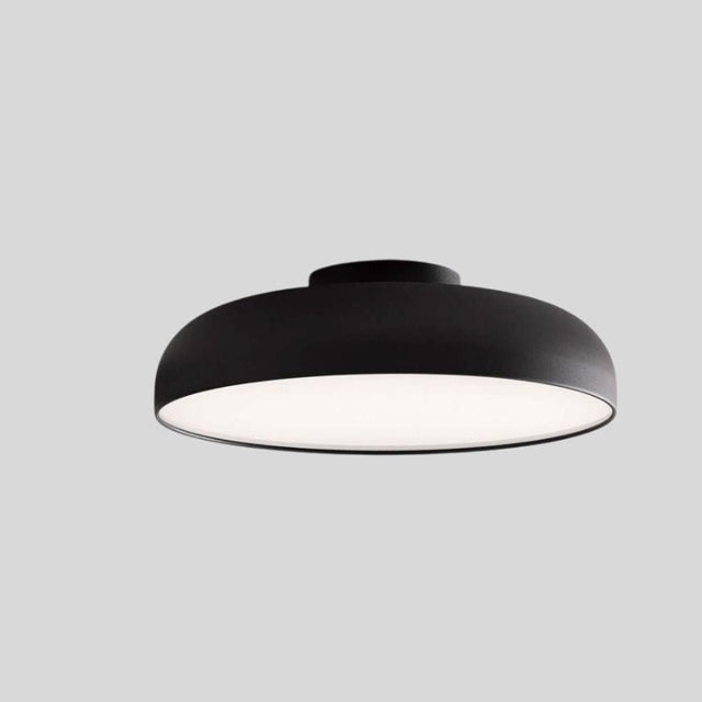"Minimalist Noira ceiling light fixture in black aluminum and steel, designed with a wide, flat shape to provide even light diffusion and a modern, sleek appearance."