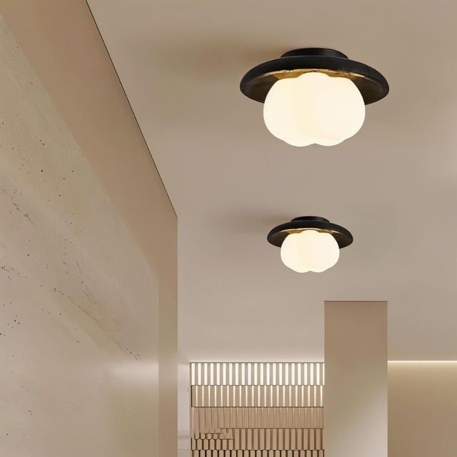 "Two ceiling lights with black travertine frames and cloud-shaped acrylic shades, illuminating a modern hallway with textured walls and ceiling."