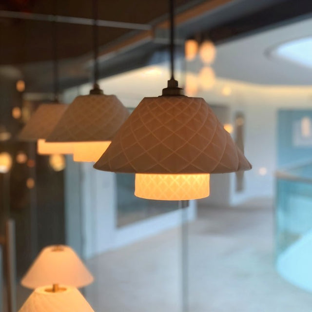 "A group of modern pendant lights with textured ceramic shades hanging in a room."