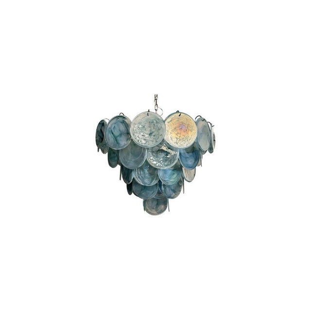 "A modern, round chandelier with cascading blue and iridescent glass discs, suspended by a chain."