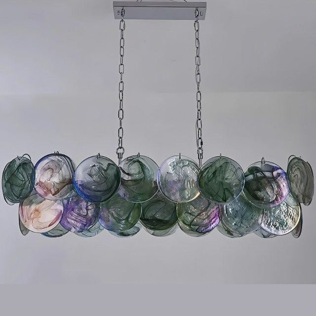 "A modern, rectangular chandelier with cascading green, purple, and iridescent glass discs, illuminated and suspended by chains."