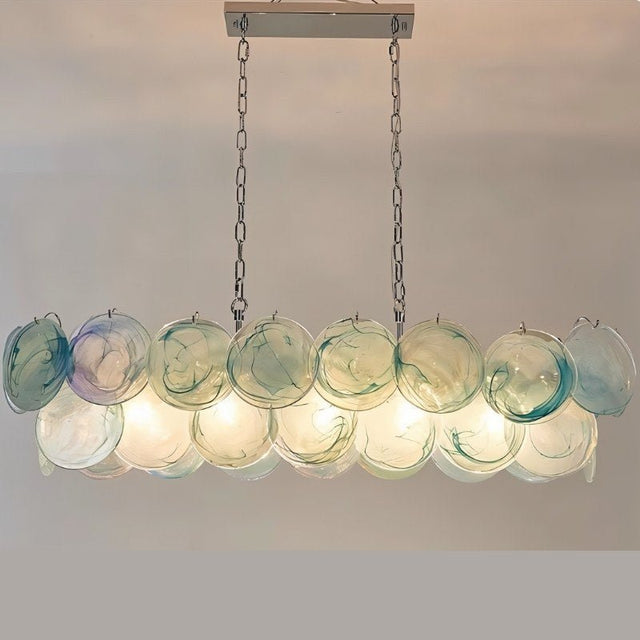 "A modern, rectangular chandelier with cascading green and iridescent glass discs, illuminated and suspended by chains."