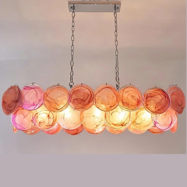 "A modern, rectangular chandelier with cascading orange and pink iridescent glass discs, illuminated and suspended by chains."