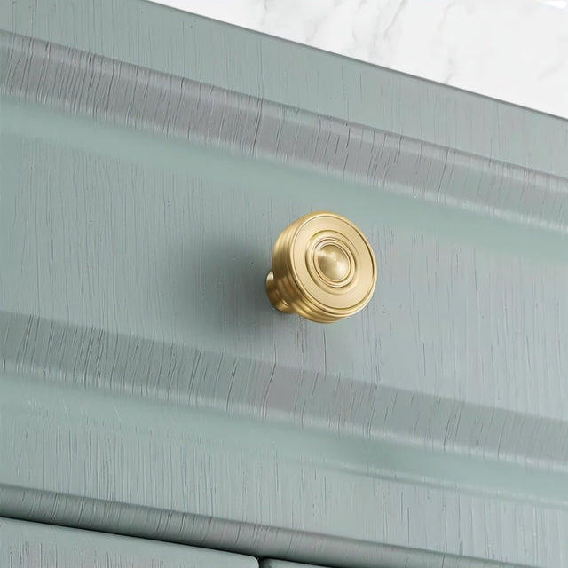 "brass cabinet knob installed on green kitchen cabinet"