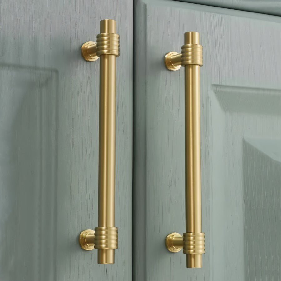 "brass pull bars installed on green kitchen cabinets"
