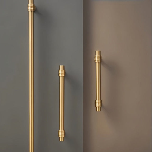 "large and small brass pull bars mounted on dark walls"