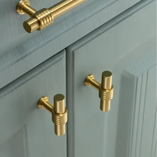 "brass pull bars and knobs installed on modern green cabinets"