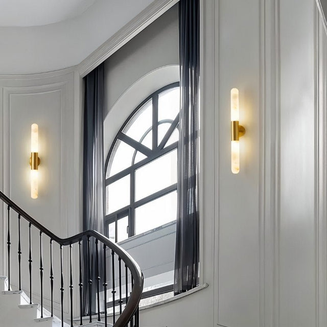 "Pair of modern gold and alabaster wall lamps illuminating a contemporary staircase with soft, ambient light."