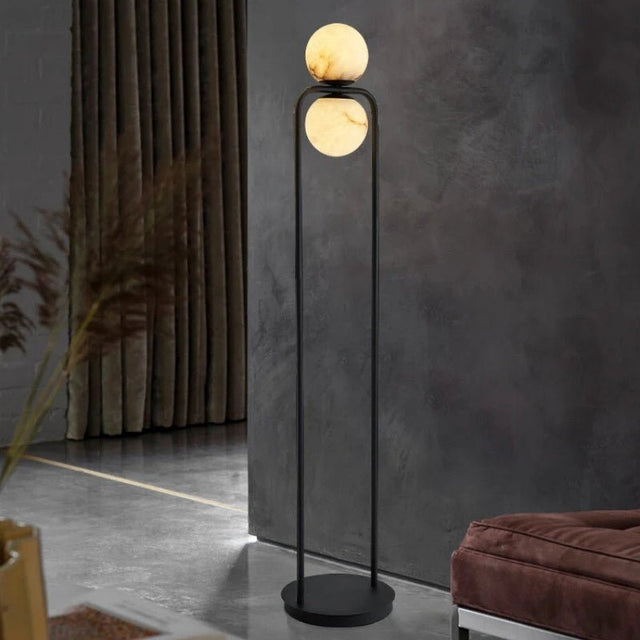 "Sleek floor lamp with minimalist aluminum frame and alabaster globe, providing ambient lighting in a modern living room with dark walls and elegant decor."
