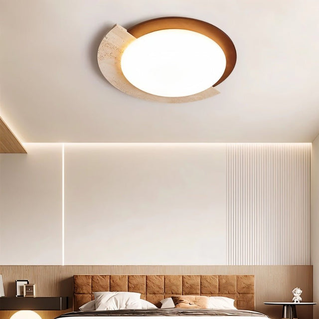 "Wabi-sabi flush mount light with travertine and white diffuser on a bedroom ceiling, providing ambient light above a tufted headboard and nightstands."