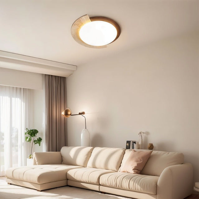 "Wabi-sabi flush mount light with a travertine stone accent and white diffuser, mounted on a living room ceiling, providing soft ambient lighting above a modern sofa."
