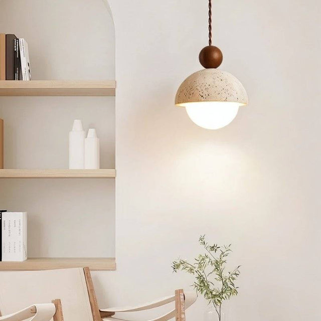 "A Palermo pendant light, made of yellow travertine with a walnut wood accent, hangs in a modern living room, providing warm, ambient light."