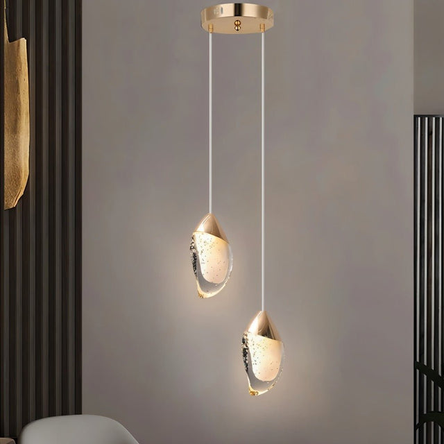 "Pair of modern pendant lights with fluid crystal forms and gold metal tops in a contemporary living room."