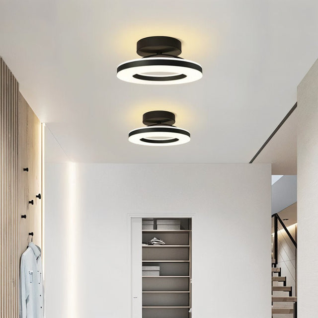 "Two modern circular ceiling lights with black dual-ring design illuminating a hallway with a closet."