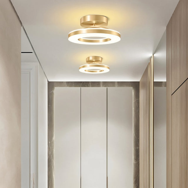 "Two modern circular ceiling lights with gold dual-ring design in a contemporary hallway with wooden doors."