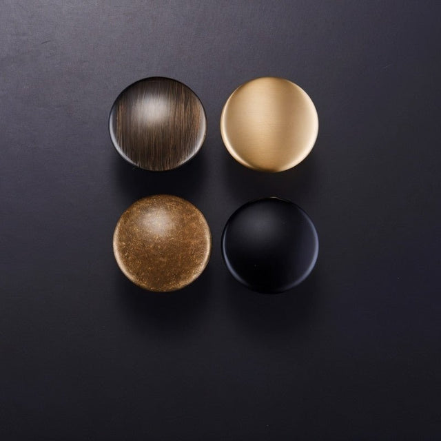 "Four dome-shaped brass cabinet knobs with flared bases in various finishes, showcasing the different design options."