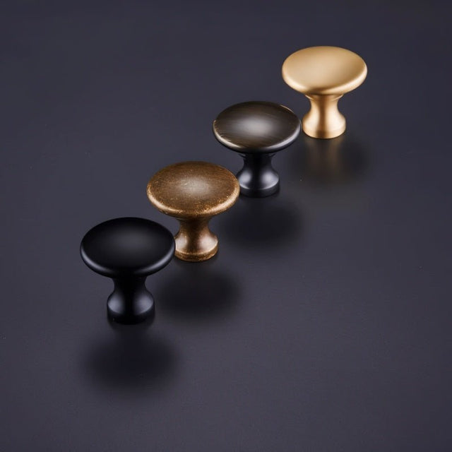 "Lineup of dome-shaped brass cabinet knobs with flared bases in various finishes, showcasing their classic design."
