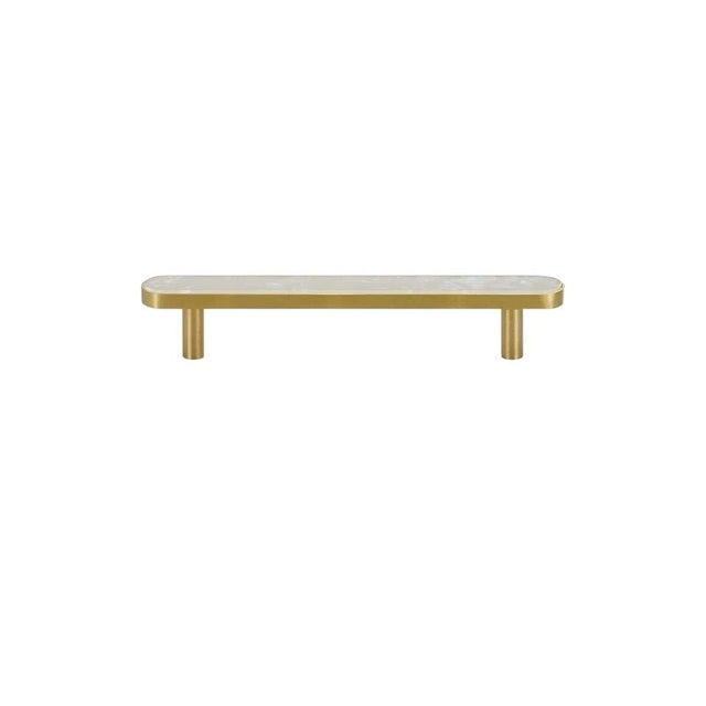 "Flat lay of a modern brass pull bar with a white shell inlay, isolated on a white background."