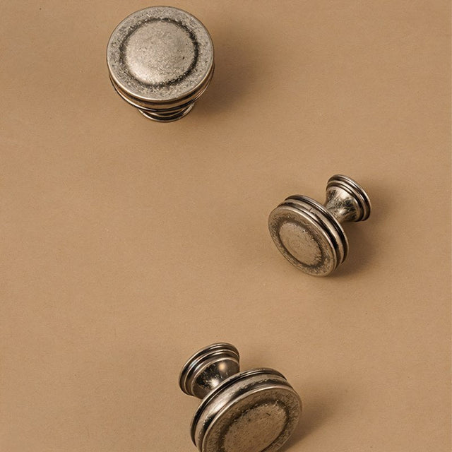 "Arrangement of vintage-inspired layered brass knobs with a distressed finish, showcasing their design and texture."
