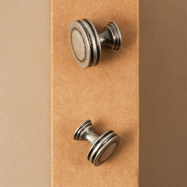 "Pair of vintage-inspired layered brass knobs with a distressed finish, suitable for classic and rustic interiors."