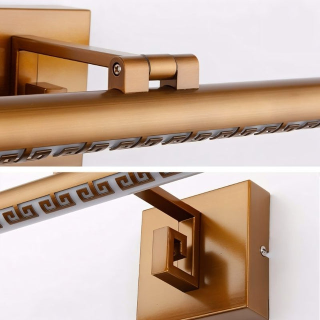 "Close-up of a gold wall lamp showing the Greek key pattern detail on the light bar and the adjustable arm mechanism."