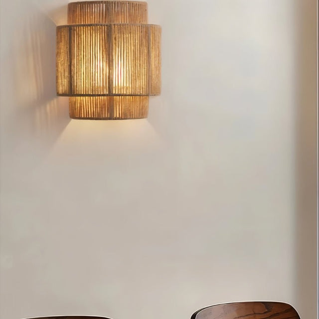 "A rustic wall lamp crafted from bamboo, rattan, and hemp, providing warm, patterned lighting in a living space."