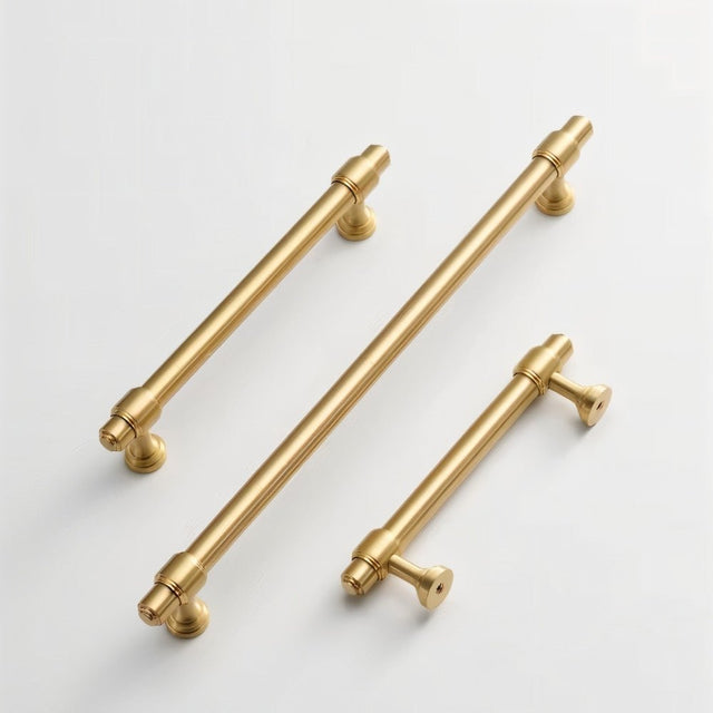 "Three solid brass pull bar handles with a cylindrical design and machined details, arranged diagonally on a light background."
